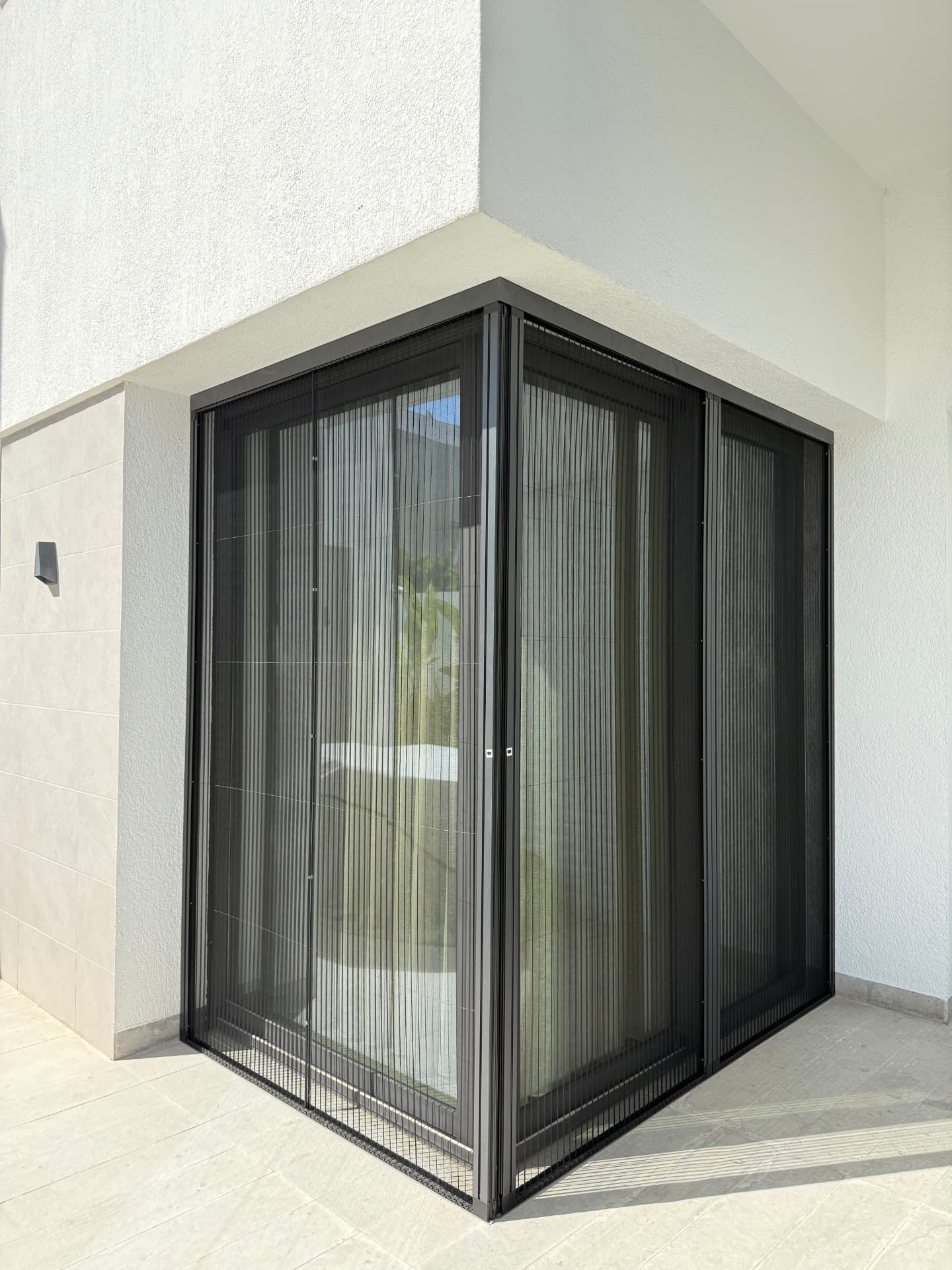Moustiquaire plissée installée en angle sur deux façades